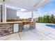 Stylish outdoor kitchen complete with grill, refrigerator, and stone accents, adjacent to a refreshing pool at 405 Winding Oaks Se Ln, Concord, NC 28025