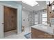 Modern bathroom with a walk-in shower, wooden accents, and white hexagonal tile flooring at 4147 Chelmsford Rd, Charlotte, NC 28211