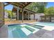 Relaxing backyard retreat featuring a pool, spa, and pergola with hanging plants at 4147 Chelmsford Rd, Charlotte, NC 28211