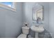 Light blue half bathroom features a pedestal sink, decorative mirror and toilet at 4941 S Hill View Dr, Charlotte, NC 28210