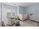 Light blue Bedroom features a white crib, comfortable armchair, and bright natural light at 4941 S Hill View Dr, Charlotte, NC 28210