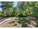 A sprawling backyard with a partially cleared space and a mix of lush greenery and mature trees at 7525 Cedarbrook Dr, Charlotte, NC 28215