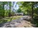 View of the home with a long paved driveway lined with mature trees and greenery at 7525 Cedarbrook Dr, Charlotte, NC 28215