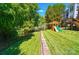 Spacious backyard with lush green grass, a playset, and bordered by a fence and mature trees at 7722 Garnkirk Dr, Huntersville, NC 28078