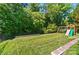 Spacious backyard features a well-manicured lawn, playset, and mature trees at 7722 Garnkirk Dr, Huntersville, NC 28078