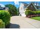 Wide driveway leading to a two-car garage, flanked by manicured shrubs and green trees at 7722 Garnkirk Dr, Huntersville, NC 28078