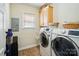 Convenient laundry room with modern washer and dryer, cabinet storage, and a bright window at 7722 Garnkirk Dr, Huntersville, NC 28078