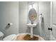 Clean powder room with a pedestal sink, oval mirror, and wood-look flooring at 7722 Garnkirk Dr, Huntersville, NC 28078