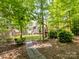 Secluded backyard featuring a stone path and covered deck, surrounded by lush greenery and mature trees at 8128 Sealey Ct, Charlotte, NC 28277