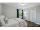 Well lit bedroom features a window with blue curtains, white closet, and hardwood floors at 8501 Flanagan Ct, Huntersville, NC 28078