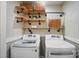 Well-lit laundry area with new front loading washer and dryer and wooden storage shelves at 8501 Flanagan Ct, Huntersville, NC 28078