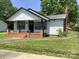 Charming single-story home features a brick chimney and inviting front porch with brick columns at 913 Winchester Ave, Monroe, NC 28110