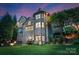 Brick home's backyard with a stone patio, fire pit, seating area, and lush landscaping at twilight at 1021 Westbury Dr, Matthews, NC 28104