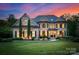 Stately brick home with manicured lawn, mature trees and lush landscaping during a beautiful twilight at 1021 Westbury Dr, Matthews, NC 28104