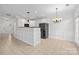 Open kitchen with white cabinets, tile flooring, modern lighting, and stainless steel refrigerator at 104 Clydesdale Ct, Matthews, NC 28104