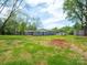Vast backyard with lush greenery, mature trees, a rock feature, and a shed, offering a private outdoor space at 105 Strickland Ln, Bessemer City, NC 28016