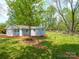 Landscaped yard with mature trees surrounding a charming one-story home with a covered front porch and painted exterior at 105 Strickland Ln, Bessemer City, NC 28016