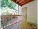 A covered porch with wooden railing overlooks a lush, green wooded backyard at 1052 Churchill Downs Ct # I, Charlotte, NC 28211