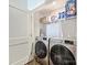 Convenient laundry room with side-by-side washer and dryer, and shelving for ample storage at 1054 Kenilworth Ave, Charlotte, NC 28204
