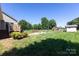 A big backyard with a deck, storage shed, firepit with chairs, and green grass on a sunny day at 109 Hunter Ct, Oakboro, NC 28129