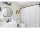 Stylish bathroom featuring modern fixtures, a round mirror, and a shower with a white curtain at 109 Hunter Ct, Oakboro, NC 28129