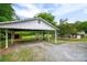 Gravel driveway leads to covered carport, offering shelter and convenience in a landscaped yard with a view of the home at 115 Patterson Rd, Kings Mountain, NC 28086