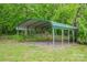 Open-sided green carport sits amidst the trees with gravel space, perfect for sheltering vehicles or providing outdoor storage at 115 Patterson Rd, Kings Mountain, NC 28086