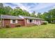 Quaint brick home with white shutters and lush green lawn, set against a backdrop of beautiful, mature trees at 115 Patterson Rd, Kings Mountain, NC 28086