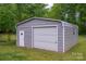 Detached garage with door and walk-in access provides secure parking and storage, nestled in a green and private backyard at 115 Patterson Rd, Kings Mountain, NC 28086