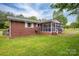 Rear view of a classic brick home featuring a screened porch and lush green grass at 115 Patterson Rd, Kings Mountain, NC 28086