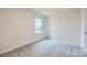 Cozy bedroom with neutral-toned walls and carpet, featuring a window with a view of the neighborhood at 118 Dorian Pl, Troutman, NC 28166