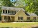 Charming two-story home with light yellow siding, black shutters, and a welcoming front porch with rocking chairs at 1338 Pell Dr, Lincolnton, NC 28092