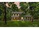 Charming two-story home with light yellow siding, black shutters, and a welcoming front porch, nestled among lush trees at 1338 Pell Dr, Lincolnton, NC 28092