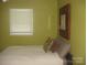 Cozy bedroom featuring a comfortable bed, window with blinds, and stylish mirror on green painted walls at 146 Barclay Ln, Mooresville, NC 28115