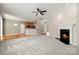 Bright living room with plush carpet, fireplace, ceiling fan, and an open floor plan to the kitchen at 14625 Lyon Hill Ln, Huntersville, NC 28078