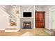Living room with a brick fireplace, wall-mounted TV, and staircase offering a comfortable gathering space at 15318 Coventry Court Ln, Charlotte, NC 28277