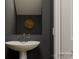 Stylish powder room featuring a pedestal sink, a round wooden wall decoration, and dark gray walls at 155 Astor St, Troutman, NC 28166