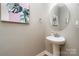 Charming powder room featuring a pedestal sink, round mirror, and elegant artwork at 15807 Foreleigh Rd, Huntersville, NC 28078