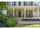 Charming front porch with rocking chairs, stone accents, and lush landscaping creates a welcoming entrance at 15807 Foreleigh Rd, Huntersville, NC 28078