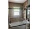 Well-lit bathroom features tub with glass door, decorative window, neutral tile and a pedestal sink at 1658 Hillcrest Ave, Lancaster, SC 29720