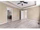 Spacious bedroom features tray ceilings with ceiling fan, light gray floors, and an ensuite bathroom for convenience at 1806 Red Bird Cir, Concord, NC 28025