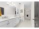 This bathroom features dual sinks, white cabinets, framed mirror, plantation shutters, and walk-in shower at 18920 Peninsula Club Dr, Cornelius, NC 28031