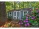 Well-maintained backyard shed with double doors and windows, surrounded by vibrant flowering shrubs, perfect for storage at 221 Grayrock Dr, Statesville, NC 28677