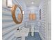 Charming bathroom with blue striped wallpaper, white sink, wooden-framed round mirror, and blue tile flooring at 2322 Hopedale Ave, Charlotte, NC 28207