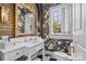 Elegant bathroom with white vanity, gold mirror, brick accent wall, and floral wallpaper at 2322 Hopedale Ave, Charlotte, NC 28207