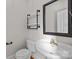 A stylish powder room features a pedestal sink, wood-look floors, and a black iron shelving unit above the toilet at 2608 Carmarthen Ct, Matthews, NC 28104