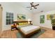 Cozy bedroom with a queen-size bed, ceiling fan, hardwood floors, and bright windows overlooking a green space at 3710 Cheleys Ridge Ln, Charlotte, NC 28270