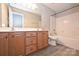 Bathroom featuring dual sinks, brown cabinets, a bathtub, and new laminate flooring at 427 Pinnacle Ln, Huntersville, NC 28078