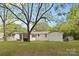 A view of the home's backyard, with bright green grass and trees and a covered carport area at 528 W Park Dr, Monroe, NC 28112