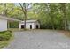 Exterior view of a new construction garage with unfinished siding and gravel driveway surrounded by lush green trees at 528 W Park Dr, Monroe, NC 28112
